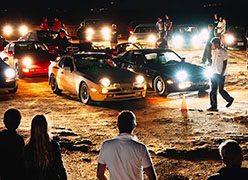 A group of people at a car meetup at night