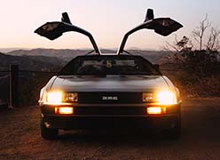 A Delorean car with both of its doors open and headlights on